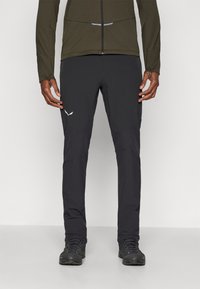 Μαύρο παντελόνι εξωτερικού χώρου σε slim fit με ελαστική μέση. Διαθέτει ενισχυμένα τμήματα γόνατος και λευκή λεπτομέρεια λογότυπου στο μηρό.