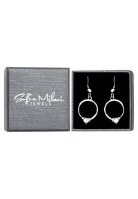 Silverf ärgade hoops med en triangulär kristallaccent, uppställda i en strukturerad grå låda med svart inredning och vitt logo.