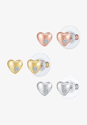 Tres pares de pendientes en forma de corazón en oro rosa, oro amarillo y plata, cada uno con un acento de cristal transparente. Acabado suave, montados en respaldos transparentes.