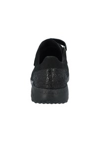 Black slip-on shoe with a textured black back panel, rubber sole, and simple design, featuring a strap across the top for secure fit.