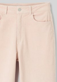 Pantalon en velours côtelé rose pâle avec poches avant, passants de ceinture et fermeture à bouton argenté au niveau de la taille.