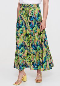 Maxi spódnica z intensywnie zielonego materiału z tropikalnym wzorem liści w niebieskim, różowym i czarnym; warstwowy krój z elastycznym paskiem na sznurku.