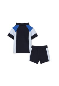 Abbigliamento a due pezzi di colore blu navy e azzurro chiaro, con una maglietta in stile polo e pantaloni corta. La maglietta presenta un colletto e un design a blocchi di colore; i pantaloni corti hanno una vita elastica.