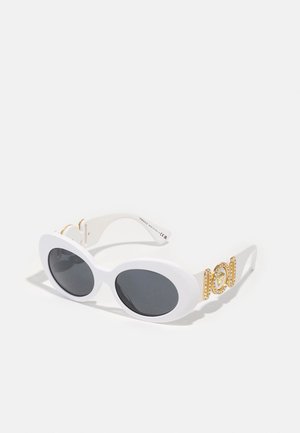 Óculos de sol ovais brancos com lentes escuras, apresentando acessórios em dourado e detalhes decorativos nas hastes. Material plástico suave.