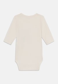 Långärmad bodysuit för baby i mjuk krämfärgad bomull. Har rund halsringning och tryckknappslåst vid nederkant för enkel påklädning.