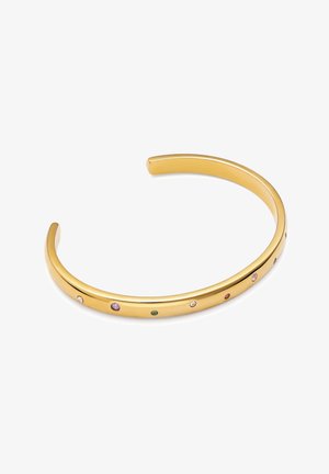 Bracelet manchette ouvert en or avec de petites pierres précieuses multicolores espacées uniformément le long de la surface extérieure sur fond blanc.