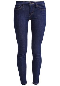 Vaqueros de mezclilla azul oscuro con corte slim, cinco bolsillos y cierre estándar de botón. Presentan costuras en contraste y una textura suave.