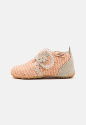 Gestreifte Kinderschuhe in Orange- und Cremetönen, mit einem blumenförmigen Akzent und einem Klettverschluss, aus weichen Materialien gefertigt.