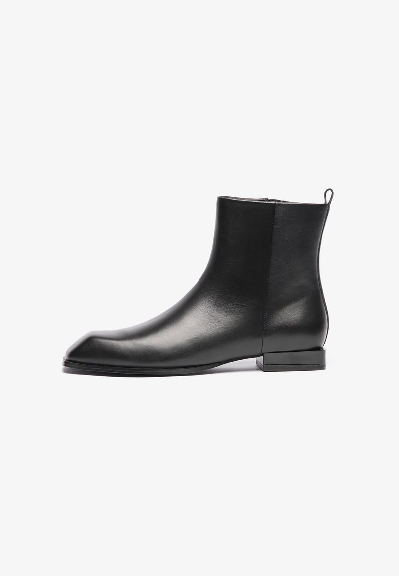 Bottine en cuir noir avec une texture lisse, un bout pointu, un design minimaliste et un petit talon carré. Comprend une languette à l'arrière pour un enfilage facile.