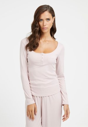 Haut à manches longues côtelé en rose doux, avec un col rond et une patte de boutonnage à trois boutons. Associé à un pantalon côtelé assorti.