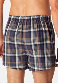 Boxer shorts avec un motif à carreaux dans des tons de bleu marine, marron et blanc. Fabriqués en tissu léger avec une ceinture élastique.