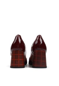 Bordowe lakierowane buty ze solidnym, kratkowanym obcasem. Szpiczasty czubek i gładka faktura kontrastują z wzorzystą powierzchnią obcasa.