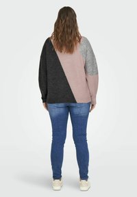 Färgat blockad tröja med grå, svart och rosa sektioner. Tillverkad av mjukt material med avslappnad passform och långa ärmar. Matchad med blåjeans.
