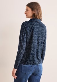 Top a maniche lunghe blu navy con un motivo testurizzato a vortice in azzurro chiaro, dotato di colletto ripiegato e una vestibilità comoda.