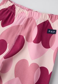 Rosa Leggings mit einem Herzmuster in verschiedenen Farbtönen, ausgestattet mit einem elastischen Bund und einem kleinen Etikett mit "P.O.P" an der Seite.