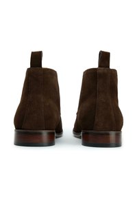 Brown suede ankle boots with a smooth finish, rounded toe, and low stacked heel. Features a pull tab at the back for easy wear.