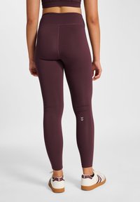 Burgunderfarvede leggings lavet af strækbart stof, høj talje, med en sømløs finish og et diskret chevronmønster nær anklen.