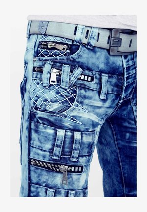 Lichtblauwe denim jeans met meerdere ritsen, een gewatteerde patch en verschillende zakontwerpen. Heeft een gestructureerde afwerking en gestikte accenten.