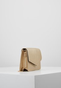 Guldig metallisk clutchväska med flikstängning, kedjerem, rektangulär form och slät yta. Minimalistisk design utan synliga mönster.