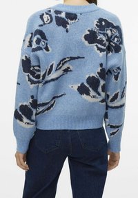 Modrý vlněný svetr s květinovými vzory v námořnické modři a krémové barvě, s volným střihem a žebrovanými manžetami. Hladká textura a design s klasickým kulatým výstřihem.