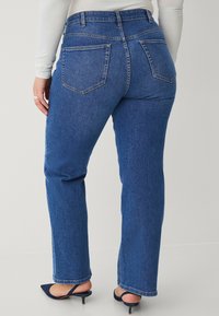Blauwe denim jeans met een hoge taille, recht gesneden benen en twee achterzakken. Gladde textuur en nette stiksels. G gedragen met hakken.