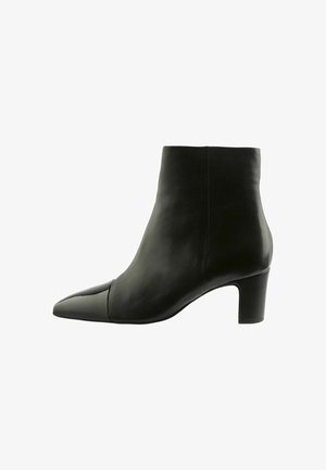 Botte de cheville en cuir noir avec un embout pointu et un talon bloc. Texture lisse, design épuré, avec un capuchon de tête brillant contrastant.