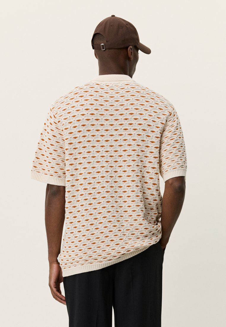 Gestricktes Kurzarmshirt in hellem Beige mit orange-braunem Rautenmuster. Mit gerippten Bündchen und entspannter Passform.