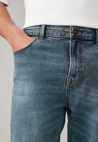 Jeans din denim de culoare albastră deschisă, cu efect de uzură vizibil, croială dreaptă, design cu cinci buzunare și cusături în contrast pe șAini.