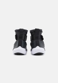 Svarta högskor med mjukt grått fleecefoder, justerbara remmar och vita gummisulor. Texturerade svarta detaljer på sidorna och baksidan.