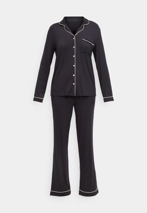 Conjunto de pijama negro con camisa de mangas largas y pantalones. Presenta ribetes blancos, cierres de botones y un bolsillo en el pecho delantero. Textura de tela suave.
