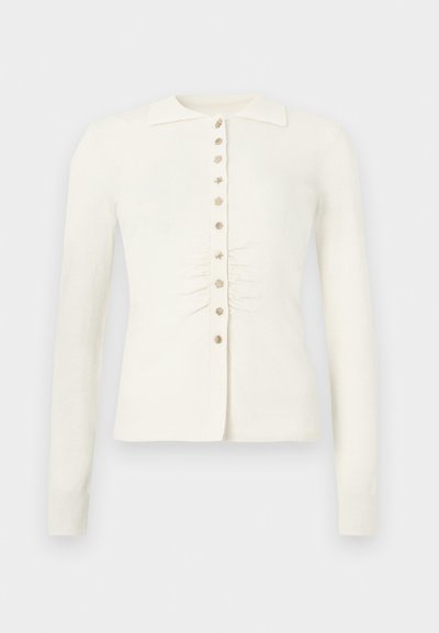 Knit cardigan in cream with a collared neckline, button closure, and gathered detailing at the waist. Long sleeves and soft texture.