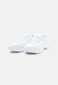 White athletic shoes with a textured synthetic upper, round toe, lace-up design, and cushioned sole. Features stitching and pull tabs.