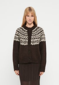 Brown knitted cardigan featuring a white patterned yoke, round collar, front buttons, and long sleeves. Soft texture with loose fit.