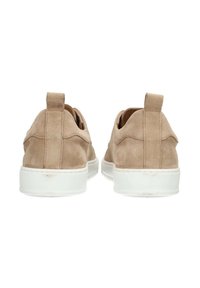 Zapatos sin cordones de ante beige con suelas de goma blanca, que presentan una textura suave y una pestaña en el talón para facilitar su puesta.
