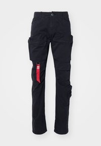 Black cargo pants with multiple side pockets, a belt loop, and a red fabric tag on the left side. Made of durable cotton material.