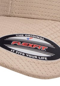 Beige pet met gestructureerde stof, voorzien van een zwart-wit ovaal logo met de tekst "FLEXFIT." Ontworpen voor comfort met een aansluitende pasvorm.