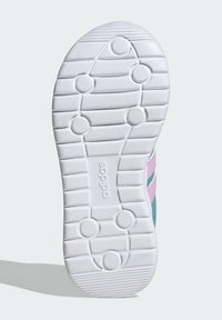 Semelle de chaussure blanche avec des motifs de traction circulaires et linéaires, nom de la marque "adidas" en relief au centre.