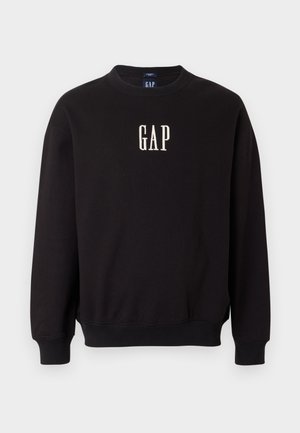 Melnā kokvilnas džemperis. Ar apaļu kaklu, garām piedurknēm un uz krūtīm dzeltenā krāsā izšūta vārds "GAP".