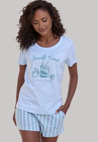 Camiseta de algodón de color azul claro con un gráfico de "Costa de Amalfi", combinada con pantalones cortos a rayas en azul claro y rosa. Mangas cortas, cuello redondo.