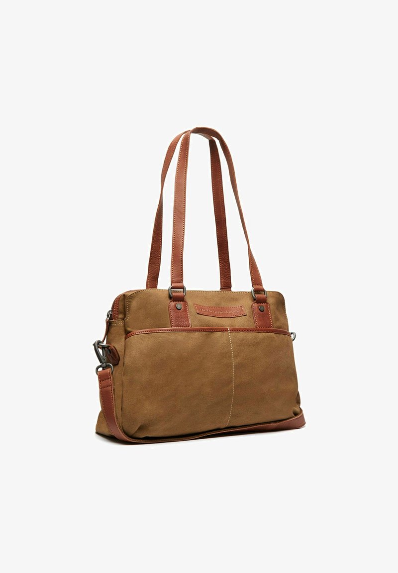Sac fourre-tout en toile beige avec des anses et des accents en cuir marron, comportant une poche avant et des détails cousus pour une texture supplémentaire.