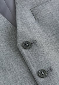 Chaleco de traje gris con una tela texturada, que presenta un cuello de muesca, dos botones negros y un bolsillo en el pecho.