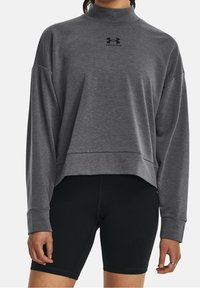 Sweatshirt gris court en tissu doux, doté d'un col haut et de manches longues. Le logo Under Armour est imprimé en noir sur la poitrine.