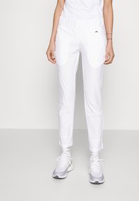 Vita sportiga byxor med elastisk midja, sidofickor och smal passform. Lättviktsmaterial med en mjuk textur.