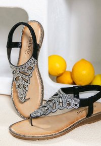 Sandalo nero con design a foglia in perline, soletta in pelle e cinturino alla caviglia. Presenta strass lungo le cinghie e una suola testurizzata.