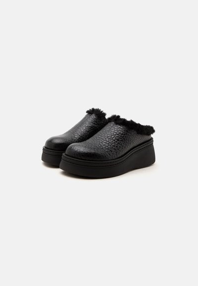 Μαύρα πλατφόρμα παπούτσια slip-on με υφή, χοντρές σόλες και μαλακή χνουδωτή επένδυση γύρω από τις άκρες, απεικονισμένα σε γωνία σε απλό φόντο.