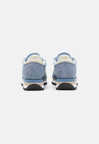 Blå semskede sneakers med polstret krage, beige detaljer og svart gummisåle. Har en logo på hælen og et enkelt design.