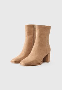 Tan suede ankle boots with a block heel, pointed toe, and side zipper closure. Smooth texture with minimal stitching details.