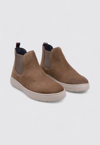 Bottines Chelsea en daim marron avec semelles en caoutchouc, dotées de panneaux latéraux élastiques et d'une languette. Texture lisse et design minimaliste.