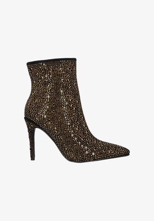 Botín de tobillo con punta afilada, tejido negro cubierto de tachuelas doradas y plateadas, y tacón de aguja. Diseño texturizado y elegante.