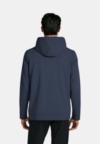 Marineblå hættetrøje med lange ærmer, sømløst design, blød tekstur og en afslappet pasform. Har justerbar snor i hætten.